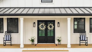 A house with a black front door, two potted plants, and two rocking chairs on either side of the entrance. - Luxury Franklin Retreat • Walk to Downtown • Front Porch (Franklin)
