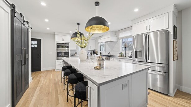 A modern kitchen with a large island, stainless steel appliances, and black bar stools. - Luxury Franklin Retreat • Walk to Downtown • Front Porch (Franklin)