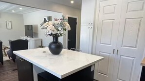 A modern kitchen with a white countertop, black cabinetry, and a vase of flowers.