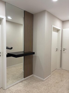 Une salle de bain moderne avec un grand miroir, un plan de toilette noir et un panneau à rayures verticales.