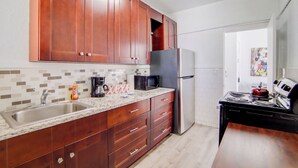 A kitchen with wooden cabinets, a stainless steel sink, a microwave, a refrigerator, and a stove. - South Beach 2BR Condo Walk to Beach  (Miami Beach)