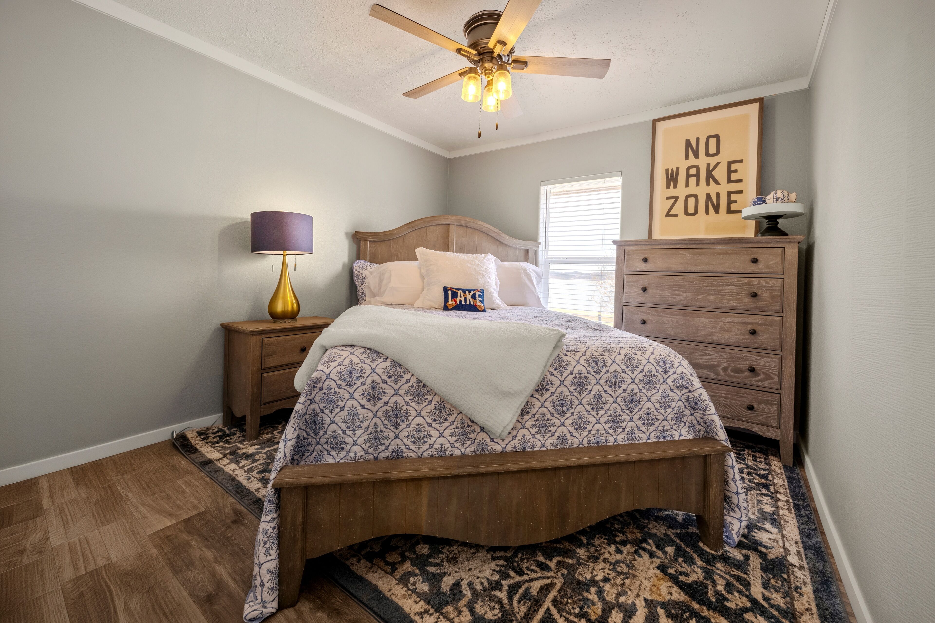 A bedroom with a bed, nightstand, dresser, and a ceiling fan.