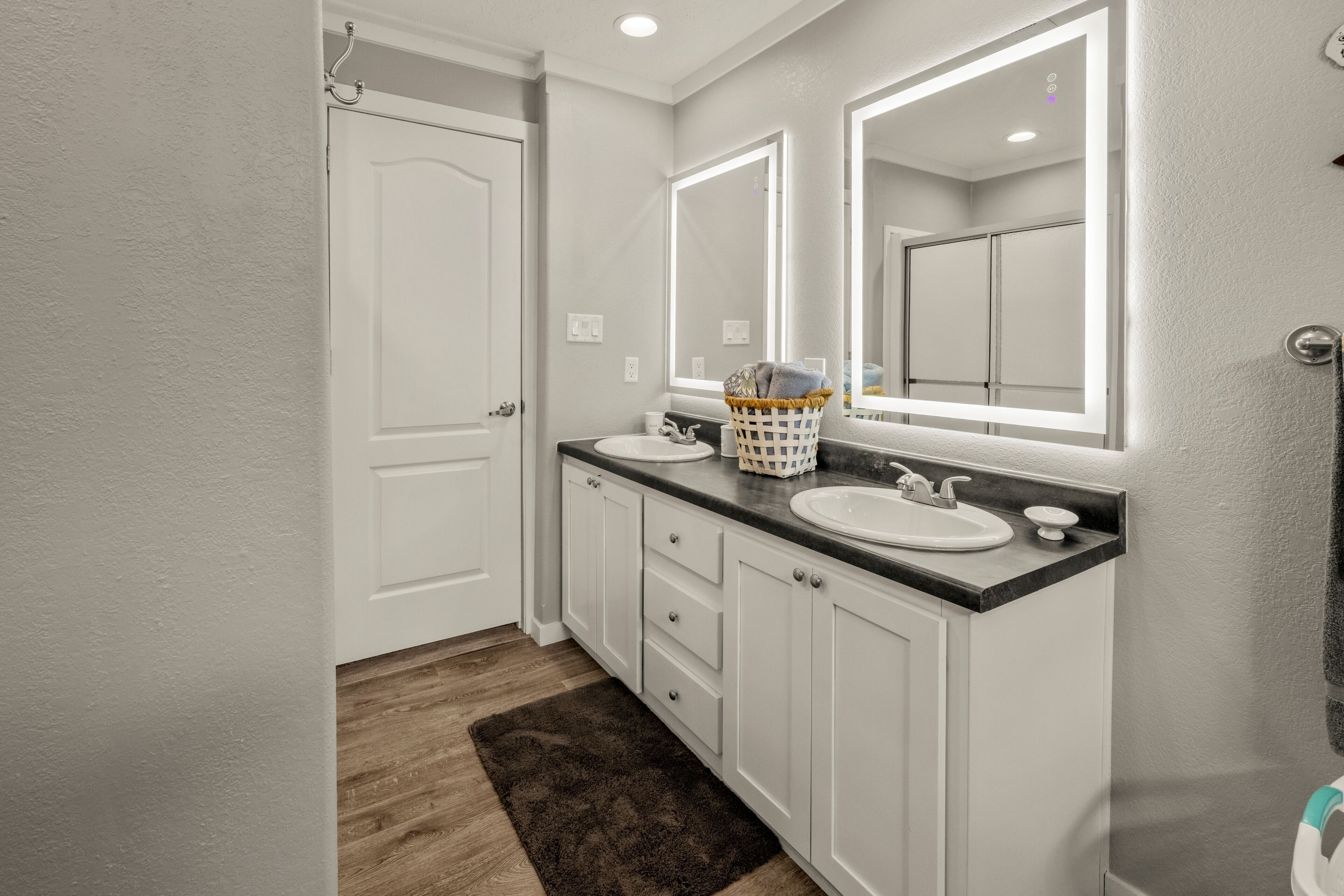 A bathroom with white cabinets, two sinks, and a large mirror.