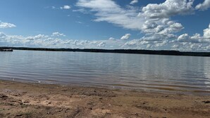 Una spiaggia con acque calme, cielo sereno e terraferma in lontananza.