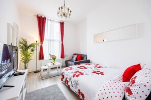 Une chambre moderne avec un grand lit, une télévision, un bureau et une chaise.