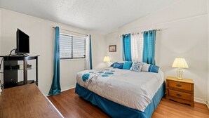 A bedroom with a bed, bedside tables, a TV stand, and curtains. - Estes Flat -Private Dock-Fish cleaning station, Fish Camp (Rockport)