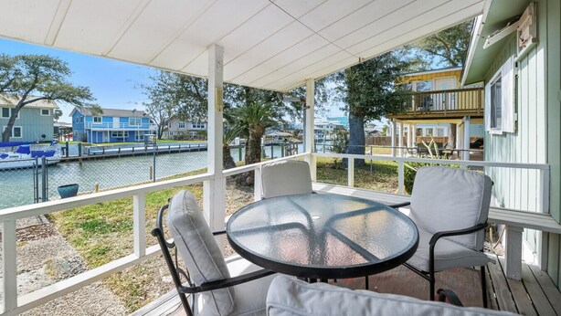 A covered outdoor seating area with a table and chairs, overlooking a body of water and buildings. - Estes Flat -Private Dock-Fish cleaning station, Fish Camp (Rockport)