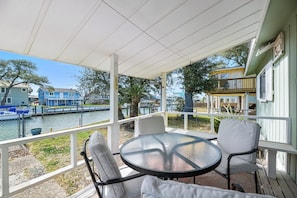 A covered outdoor seating area with a table and chairs, overlooking a body of water and buildings. - Estes Flat -Private Dock-Fish cleaning station, Fish Camp (Rockport)