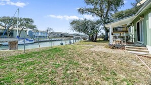 A waterfront property with a grassy yard, a dock, and a building with a porch. - Estes Flat -Private Dock-Fish cleaning station, Fish Camp (Rockport)