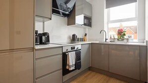 Una cocina moderna con horno empotrado, microondas y cafetera.