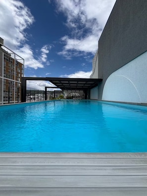 Una piscina con una vista despejada del cielo y edificios al fondo.