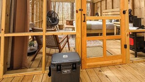 Une cabane en bois avec un plafond haut et un toit en verre, comprenant un lit, un bureau et une chaise.