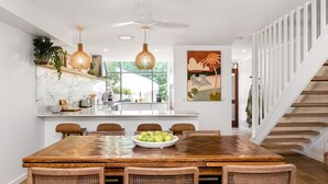 Eine moderne Küche mit einer großen Holzinsel, Pendelleuchten und einem Essbereich mit Holztisch und -stühlen.