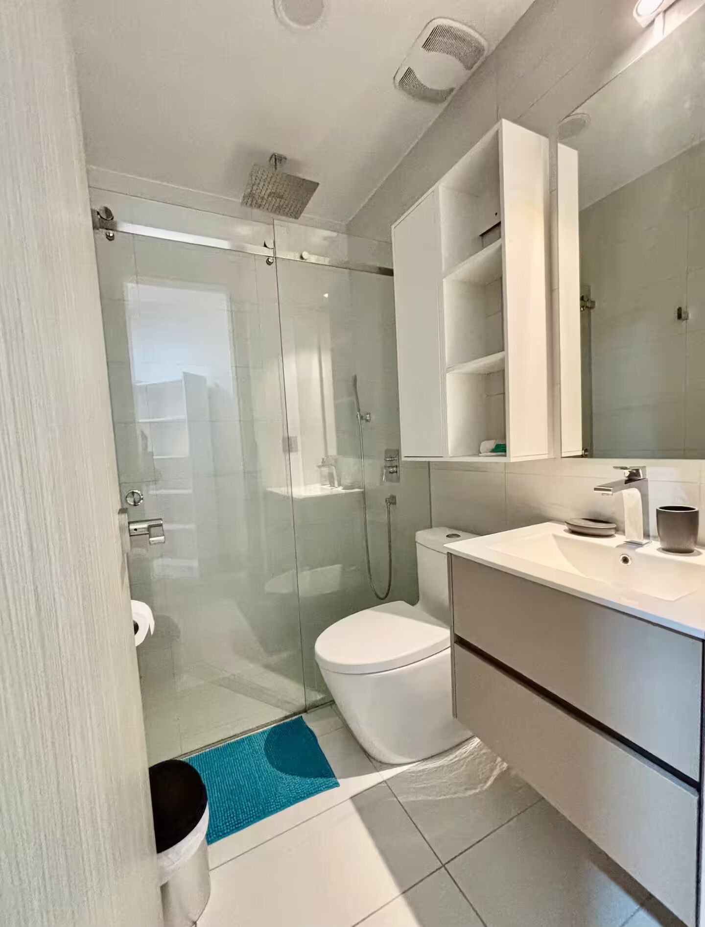 A modern bathroom with a glass-enclosed shower, a toilet, and a vanity with a mirror.