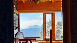 Interno in legno con un'ampia finestra che si affaccia su una vista montana.