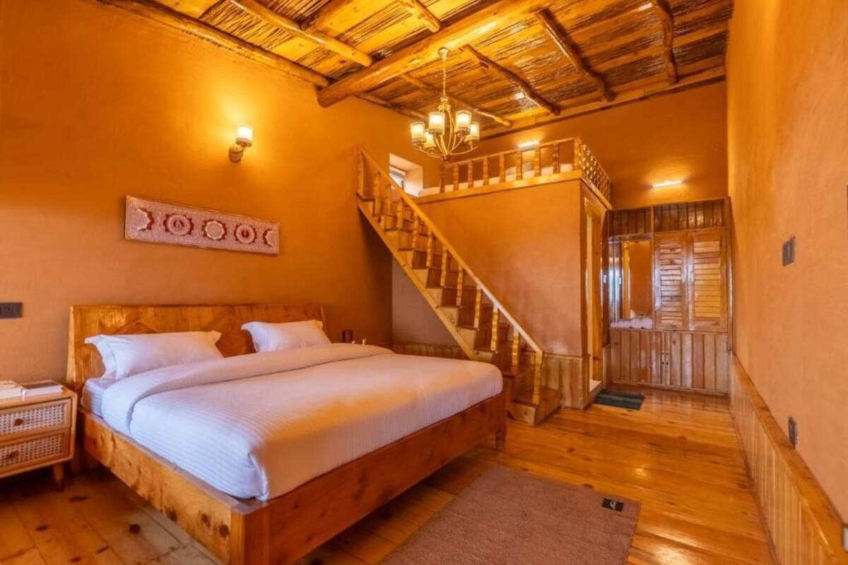 Ein Bett mit Holzkopfteil, eine Treppe und eine Wandleuchte.