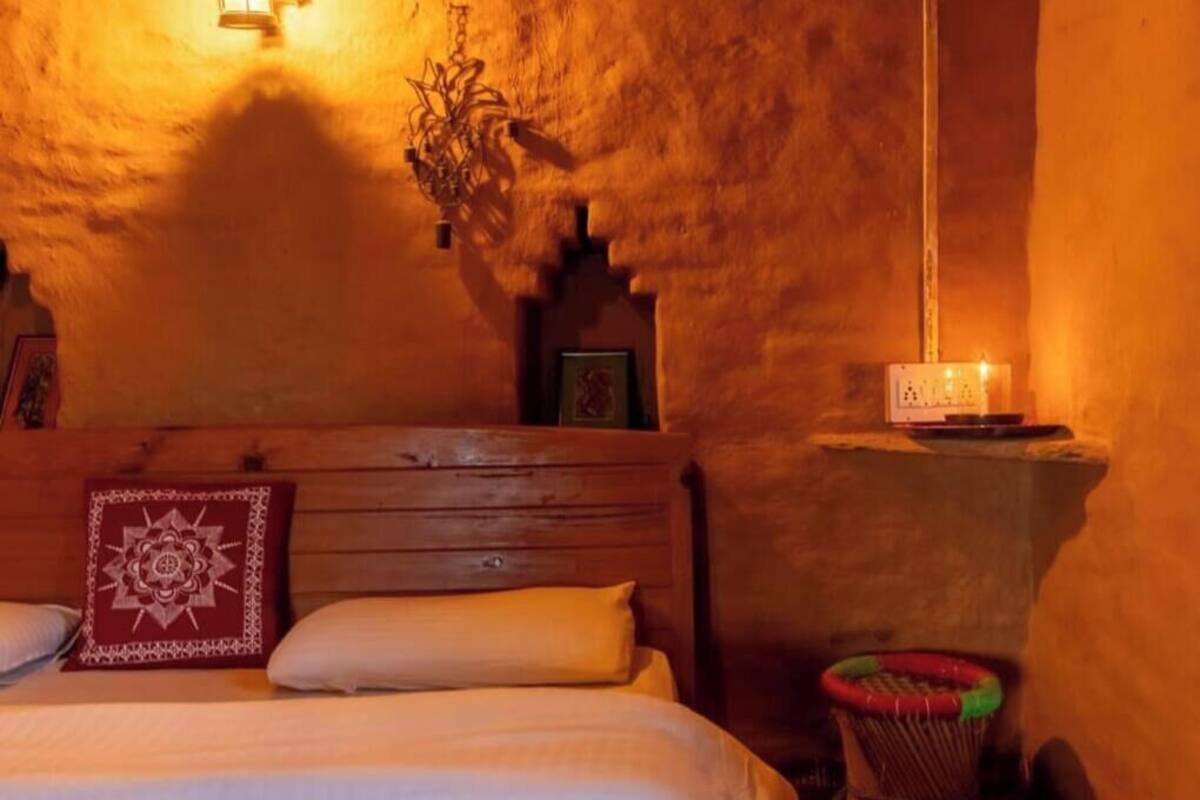 Ein gemütliches Zimmer mit einem hölzernen Bett, einer Wandleuchte und einem kleinen Tisch mit Kerze.