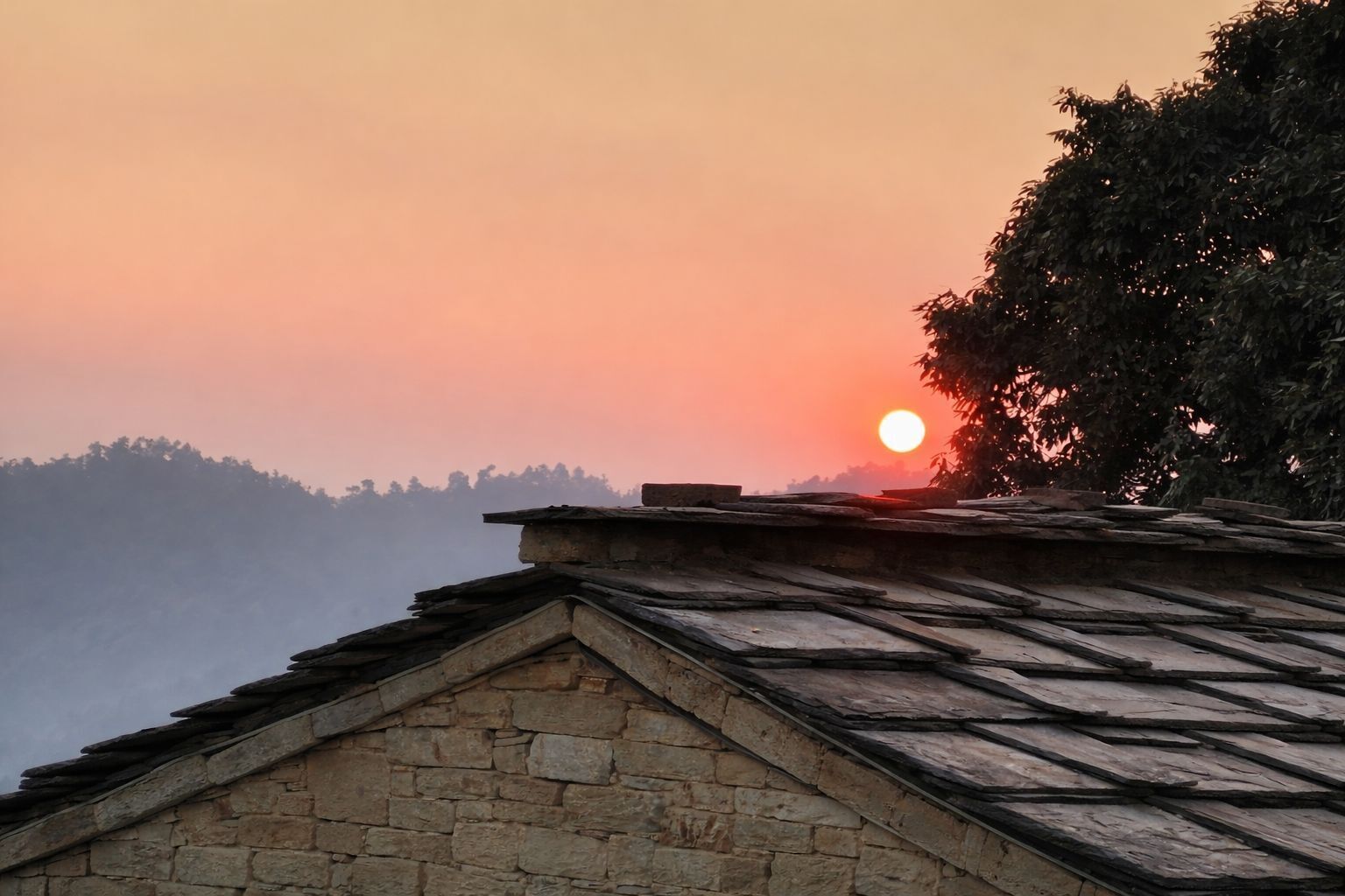 Un edificio de piedra con techo inclinado, con vistas a un área boscosa y un atardecer de fondo.