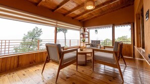 Una stanza con pavimento in legno, un tavolo e sedie, ampie finestre e una lampada a soffitto.