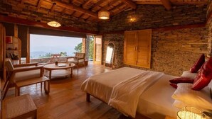 Un'ampia camera da letto con un letto grande, arredi in legno, pareti in pietra e vista sull'esterno.