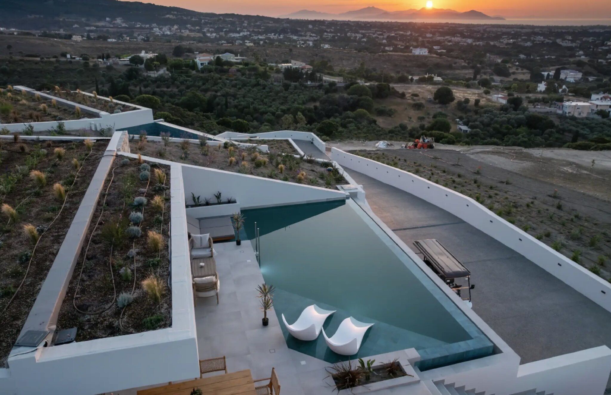 Ein modernes Resort mit Poolbereich, Sitzgelegenheiten im Freien und Blick auf die umliegende Landschaft.