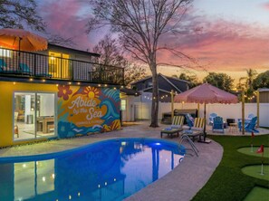 Ein Wohnhaus mit Schwimmbad, Sitzgelegenheit im Freien und einem farbenfrohen Wandbild.