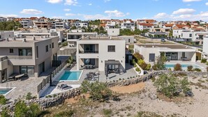 Una zona residenziale moderna con diversi edifici, una piscina e un paesaggio roccioso.
