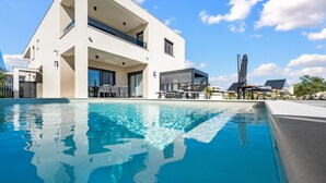 Un edificio moderno con piscina, area salotto all'aperto e cielo sereno.