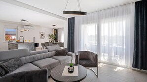 Un soggiorno moderno con un divano grigio, un tavolino rotondo e un'area pranzo con cucina sullo sfondo.