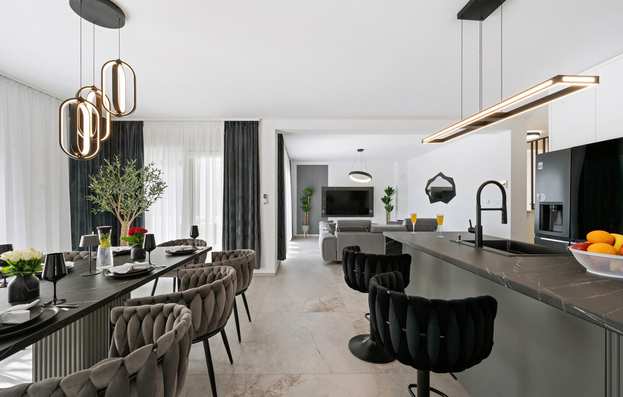 Eine moderne Küche mit Essbereich, inklusive Bar, Sitzgelegenheiten und einem großen Fernseher.