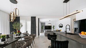 Una cucina moderna con zona pranzo, caratterizzata da un bancone, posti a sedere e un grande televisore.