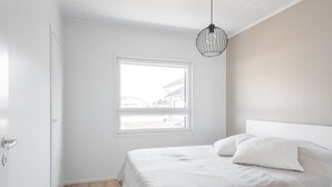 A minimalist bedroom with a large window, a bed with white bedding, and a hanging light fixture. - Nice house with relaxed athmosphere (Uusimaa)