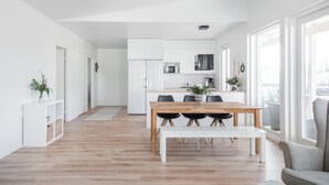 A modern, minimalist living space with a wooden dining table, a bench, and a view of the city through large windows. - Nice house with relaxed athmosphere (Uusimaa)