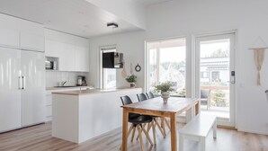 A modern kitchen with white cabinetry, a wooden island, and a dining area with a table and chairs. - Nice house with relaxed athmosphere (Uusimaa)