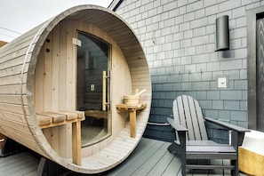 A wooden sauna with a curved entrance, a wooden bench, and a sauna chair on a deck. - The Louie Boutique Motel (Newport)