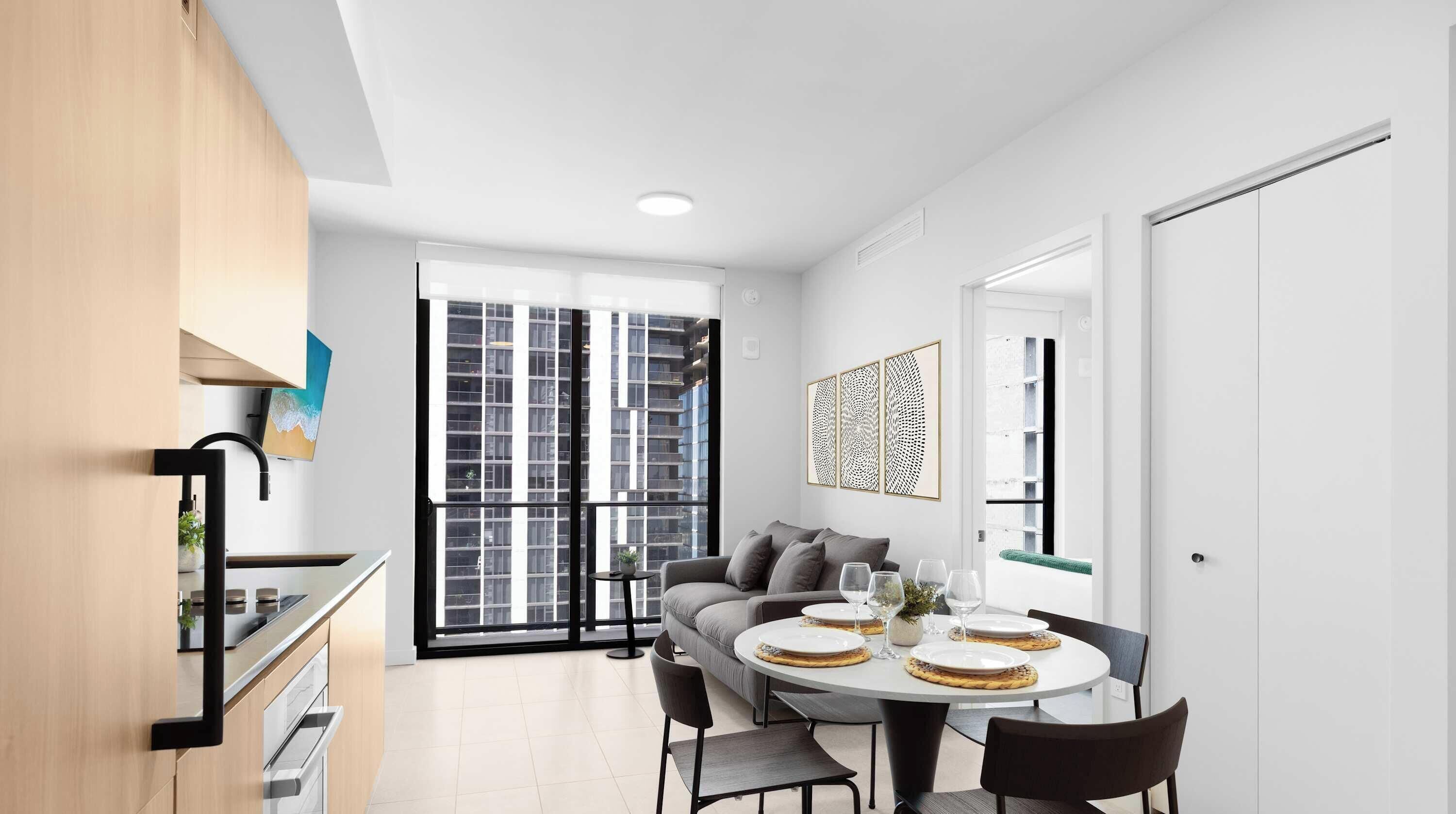 A modern kitchen with a dining area, large windows, and a view of a building.