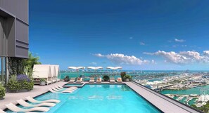A rooftop infinity pool with lounge chairs and umbrellas, overlooking a cityscape and coastline. - Light-Filled 1BR with Private Balcony Urban Chic (Miami)