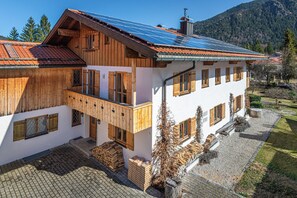Ein zweistöckiges Holzhaus mit Balkon, Solaranlage und Bergblick.