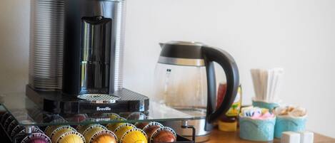 A coffee machine with a Breville brand, a glass carafe, and a tray of coffee capsules.