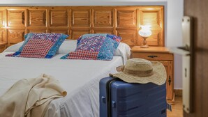 A neatly made bed with patterned pillows, a bedside lamp, and a suitcase with a hat on top. - CHL El Faro, next to the Puerto Naos beach (Puerto Naos, Los Llanos de Aridane)