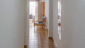 A hallway with a wooden chair and a table, leading to a balcony with a view. - CHL El Faro, next to the Puerto Naos beach (Puerto Naos, Los Llanos de Aridane)