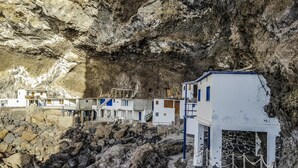 A coastal hotel with white buildings and blue accents, situated on rocky terrain with a cave-like background. - CHL El Faro, next to the Puerto Naos beach (Puerto Naos, Los Llanos de Aridane)