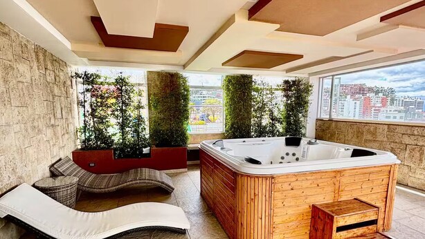 Un moderno salón en la azotea con jacuzzi, zona de estar y vistas a la ciudad.