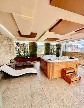 Una moderna terrazza panoramica con idromassaggio, zona salotto e vista sulla città.