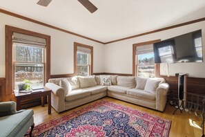 A living room with a sectional sofa, a patterned rug, and a flat-screen TV.