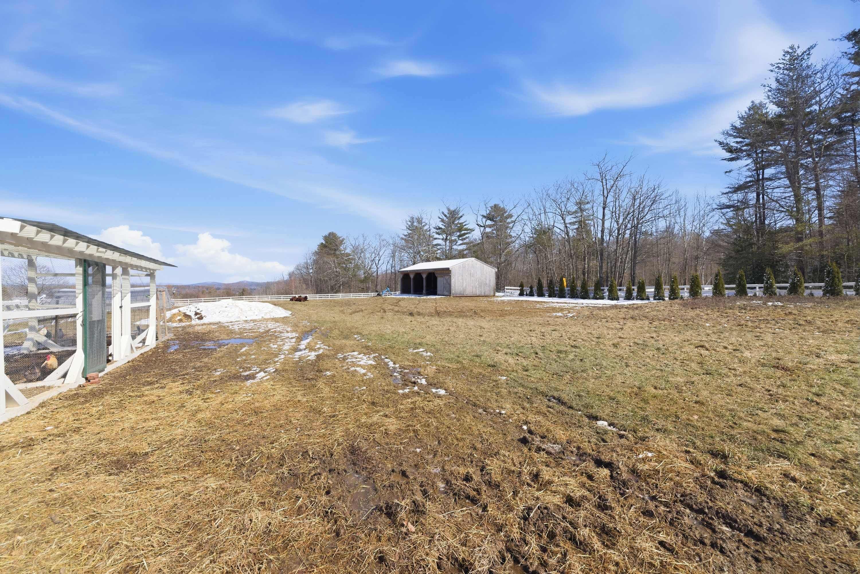 Une propriété rurale comprenant une grange, des champs ouverts et un espace clôturé.