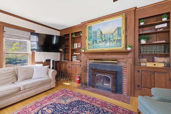 The living room fireplace and built-in bookshelves, with the oil painting above the mantel and the flat-screen TV ready for a quiet evening in.