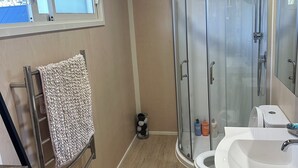 A modern bathroom with a glass-enclosed shower, a white sink, and a towel rack.