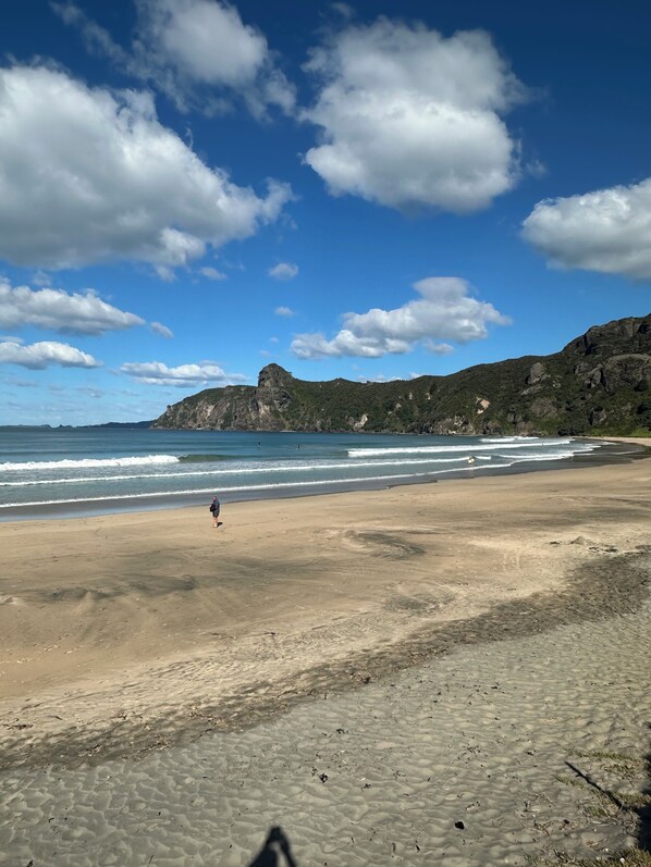 Ein Strand mit blauem Himmel, Wellen und felsigen Klippen.