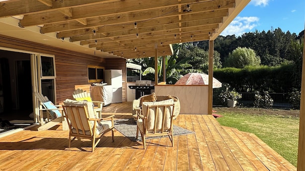 A wooden deck with outdoor furniture, a grill, and a pergola structure.